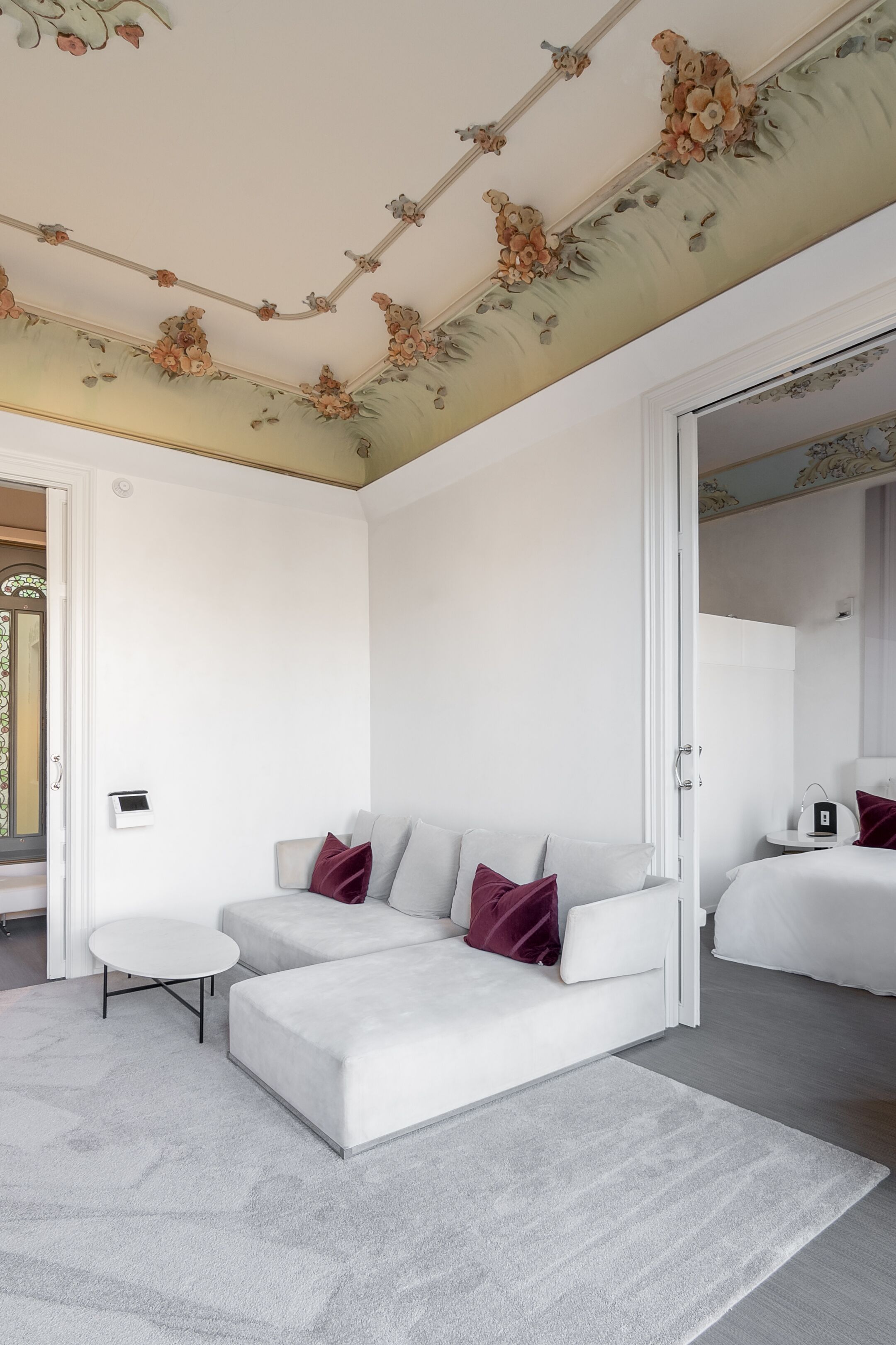 Een moderne slaapkamer met een witte bank, een klein rond tafeltje en een grote spiegel.