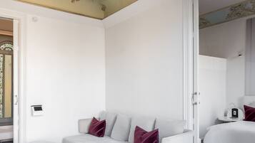 Een moderne slaapkamer met een witte bank, een klein rond tafeltje en een grote spiegel.