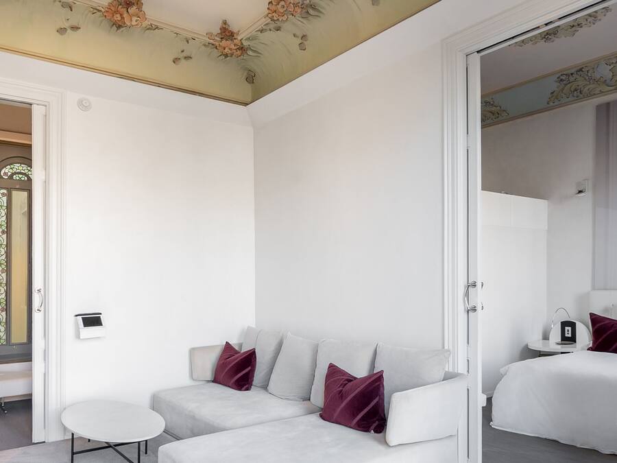 Een moderne slaapkamer met een witte bank, een klein rond tafeltje en een grote spiegel.