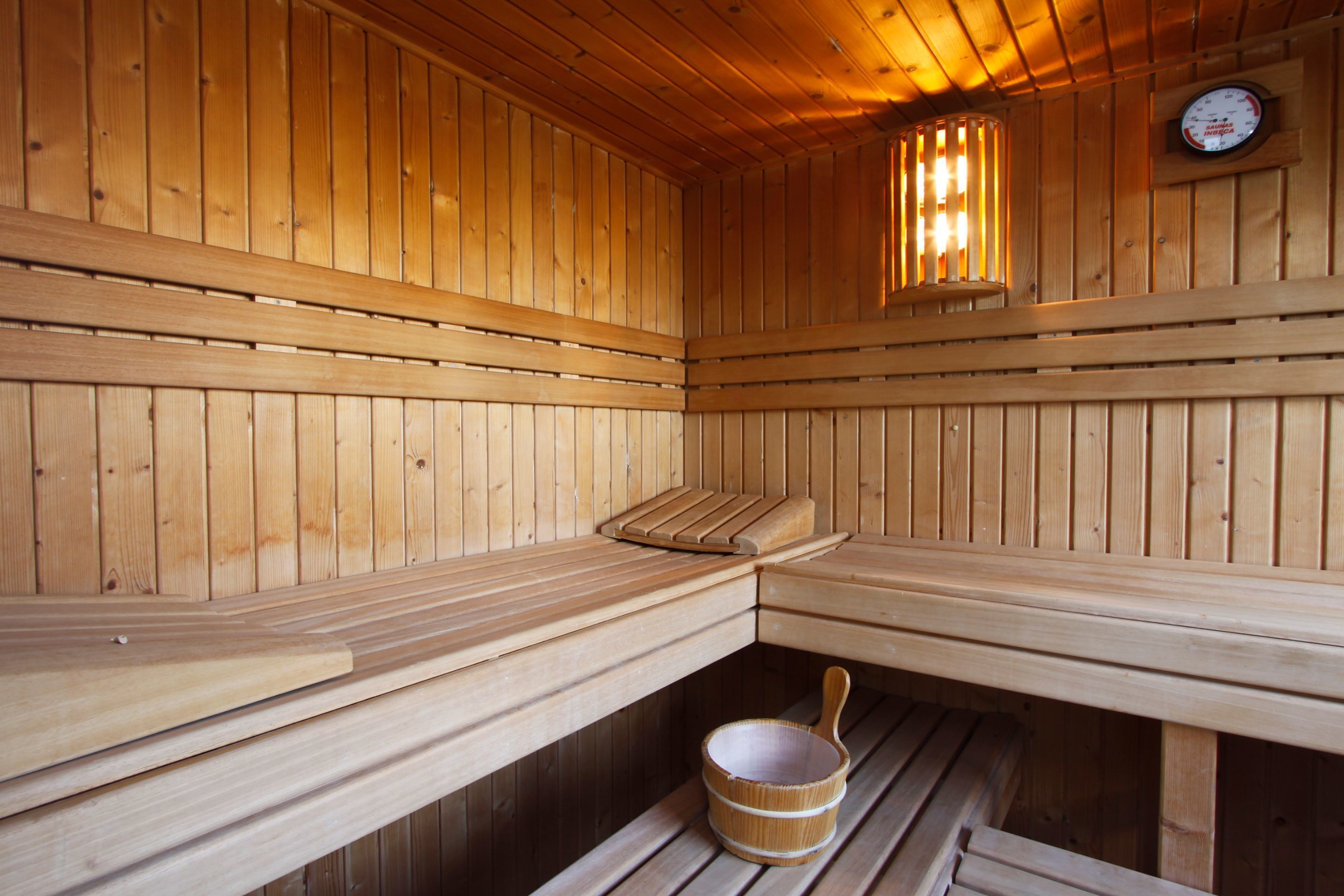 Una sauna de madera con bancos y un pequeño balde de madera.
