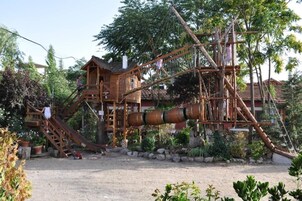 Una estructura de madera rústica con una escalera, un tobogán y un objeto cilíndrico grande.