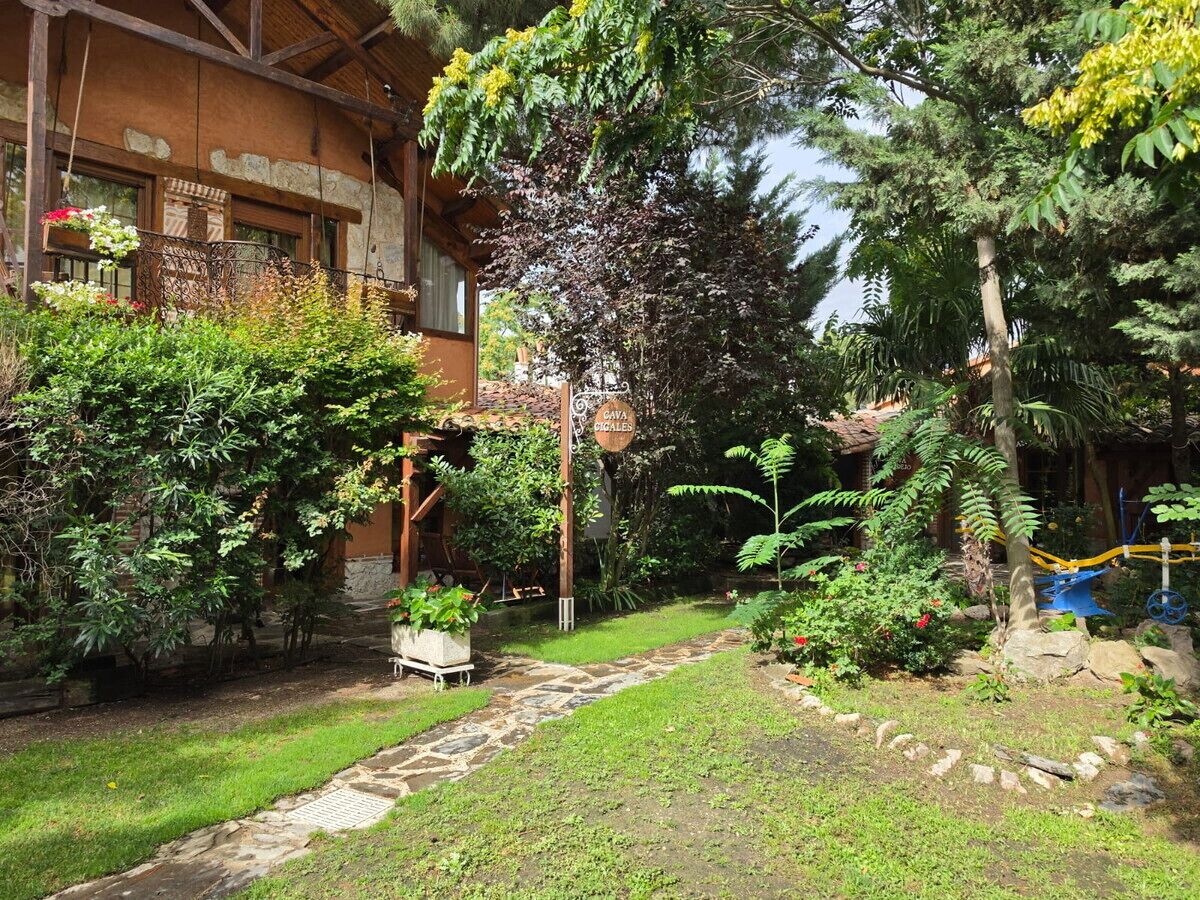Ein Garten mit einem Kiesweg, einer hölzernen Pergola und einem Schild mit der Aufschrift 'CAVA CAGALES'.