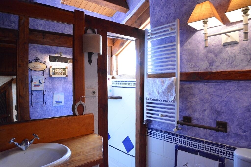 A bathroom with a wooden vanity, a sink, a mirror, a towel rack, and a towel warmer.