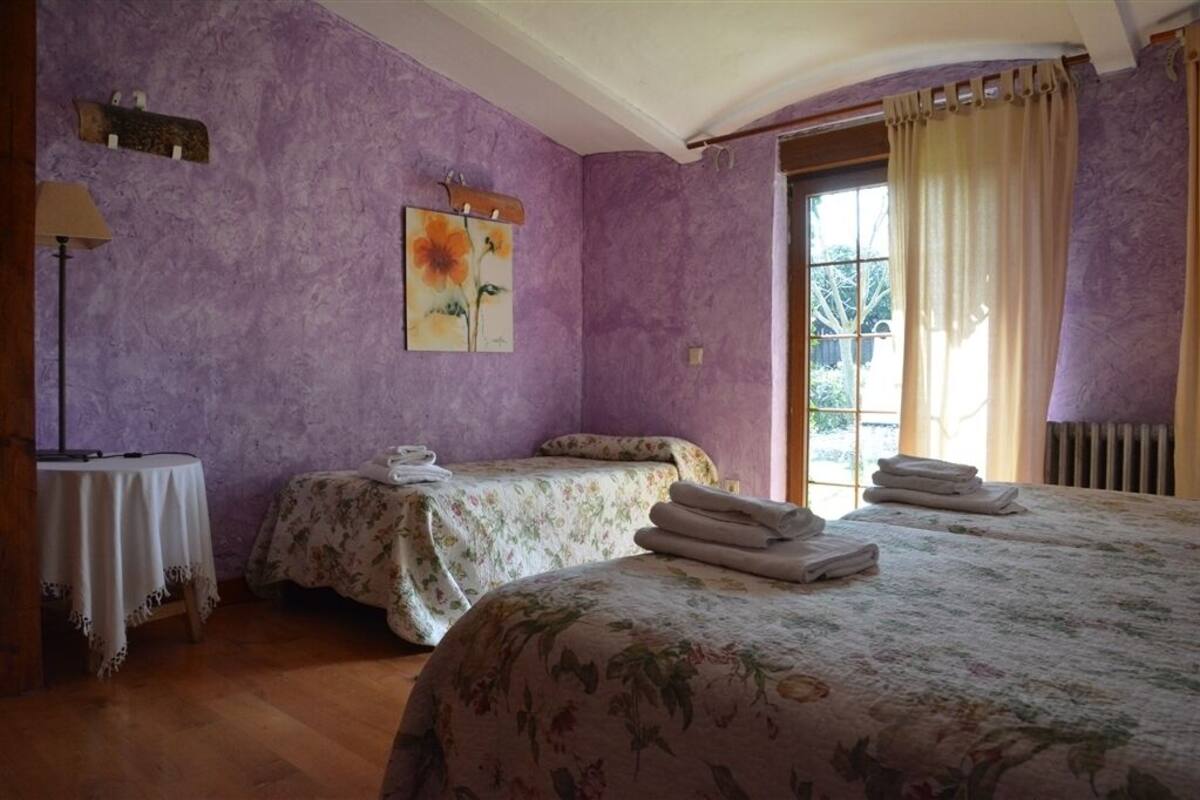 Een kamer met twee bedden, een tafel en een raam met gordijnen.