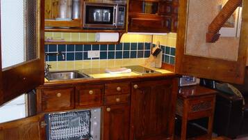 Una cocina compacta con gabinetes de madera, un microondas, un fregadero y un lavavajillas.