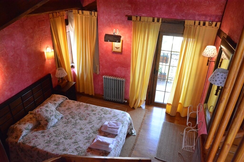 Quarto com cama, cortinas, radiador e luminária.