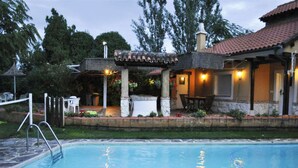 A swimming pool with a patio area, outdoor seating, and a covered section with lights. - Hospedium Hacienda Las Cavas (Olmedo)
