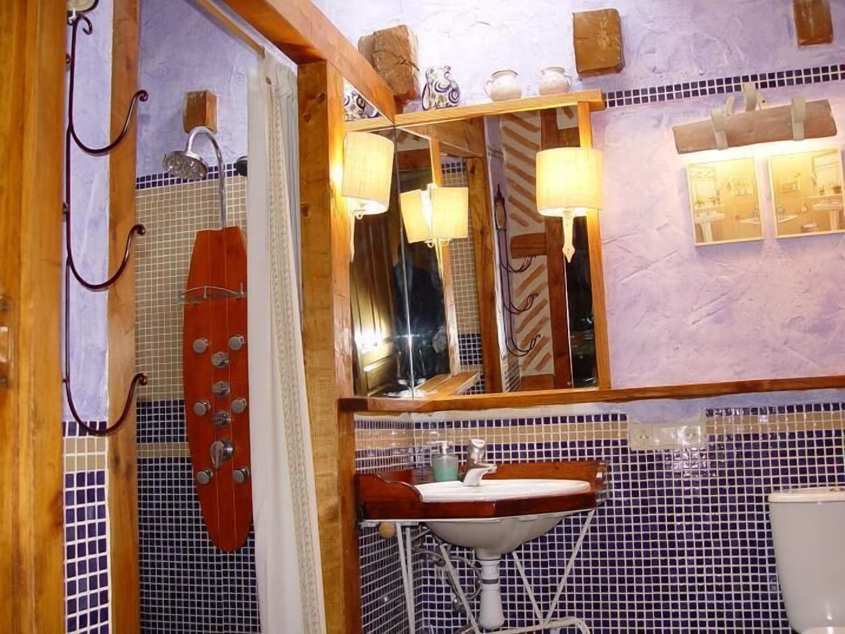 Een badkamer met een houten wastafelmeubel, een wastafel, een spiegel en een douchegedeelte.