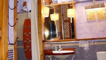 Een badkamer met een houten wastafelmeubel, een wastafel, een spiegel en een douchegedeelte.