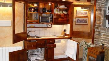 Une cuisine compacte avec des meubles en bois, un four à micro-ondes encastré et un réfrigérateur.