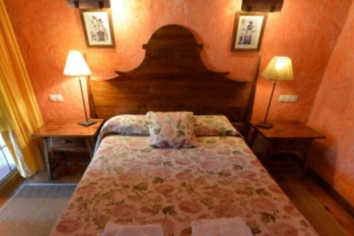 Een bed met bloemenbeddengoed, twee nachtkastjes en lampen.