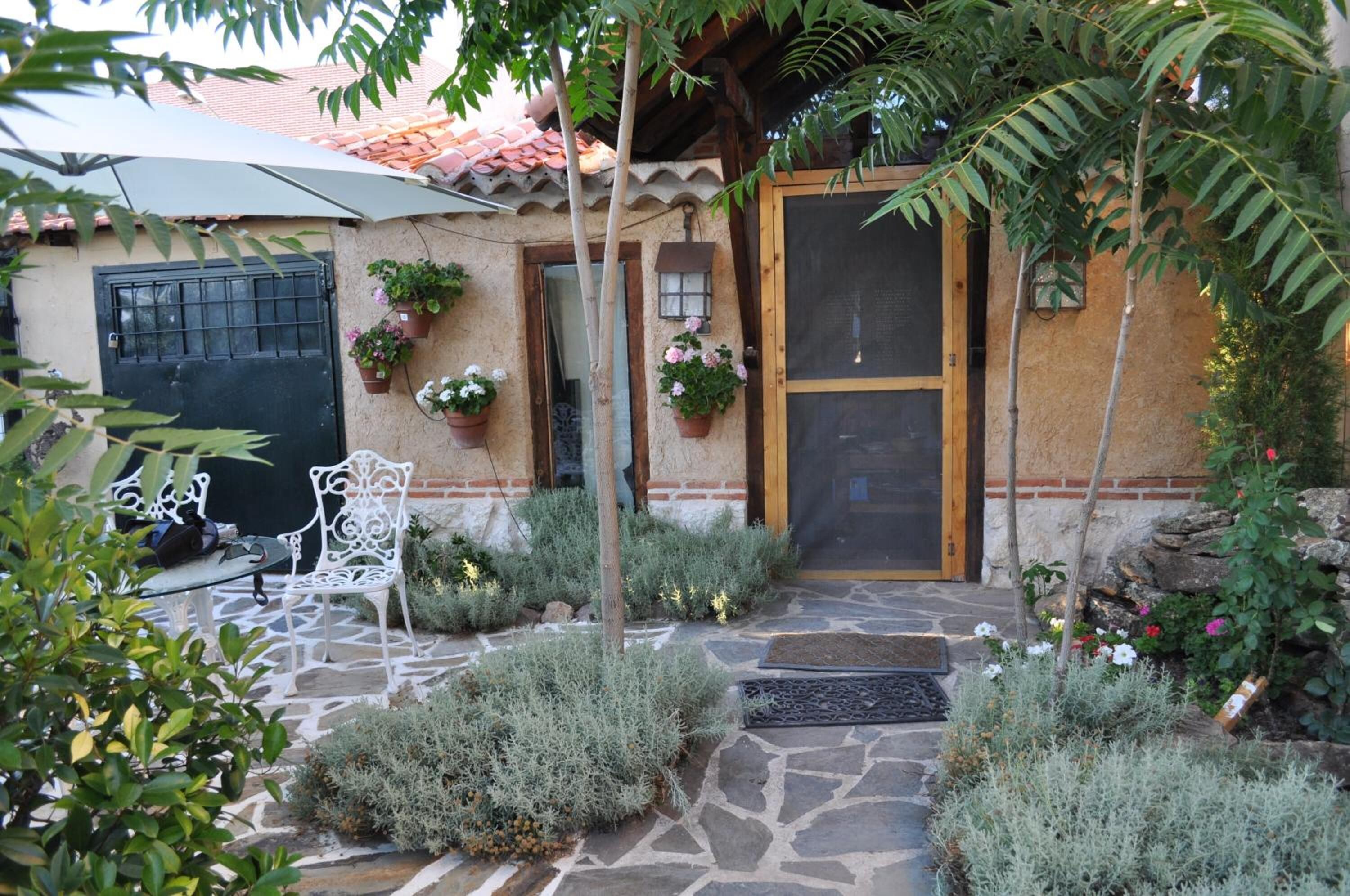Un patio de piedra con mobiliario exterior, una puerta con mosquitero y plantas en macetas.