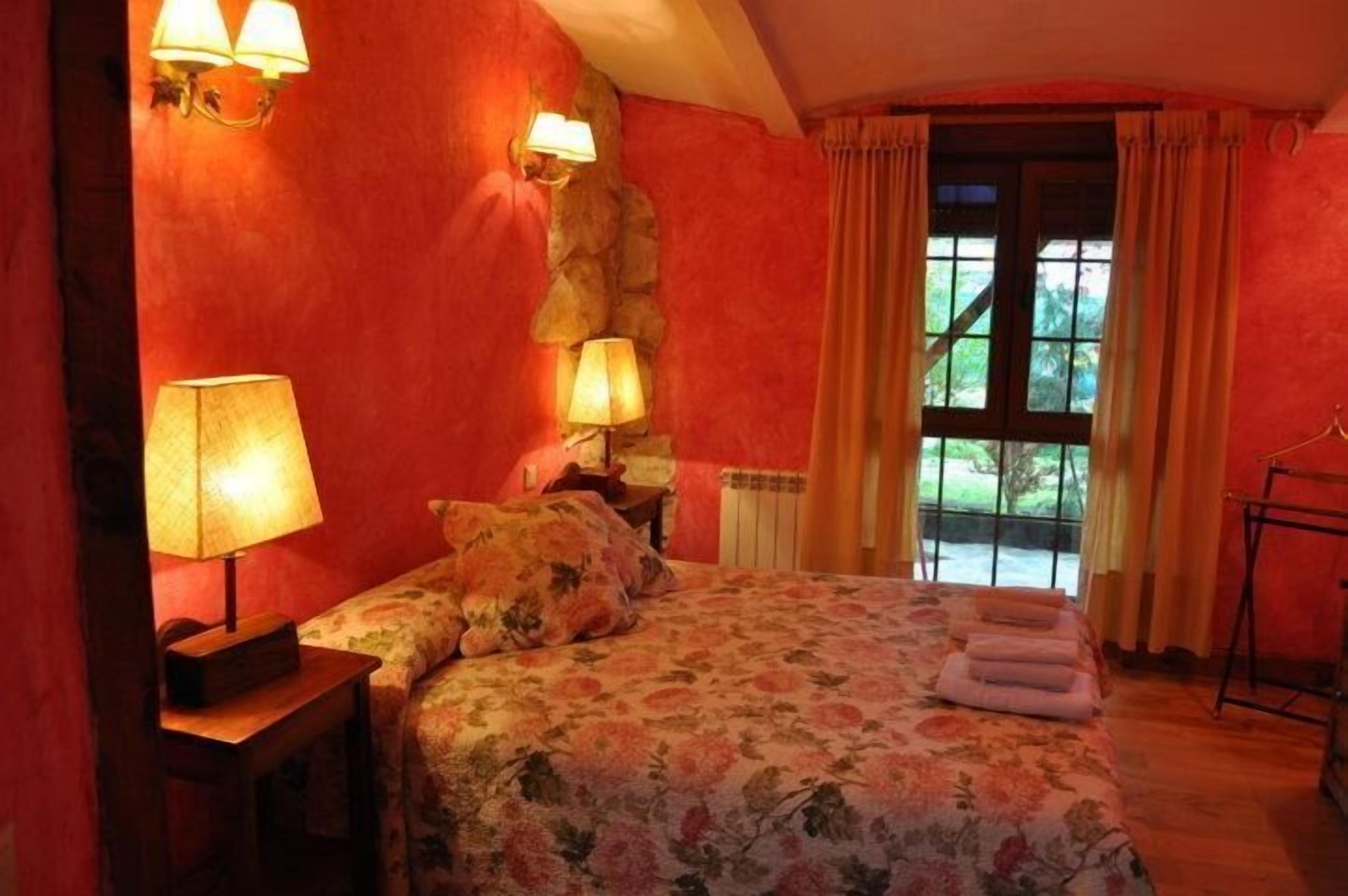 Une chambre à coucher avec un lit, deux lampes de chevet, une table de chevet, une fenêtre avec des rideaux et un plancher en bois.