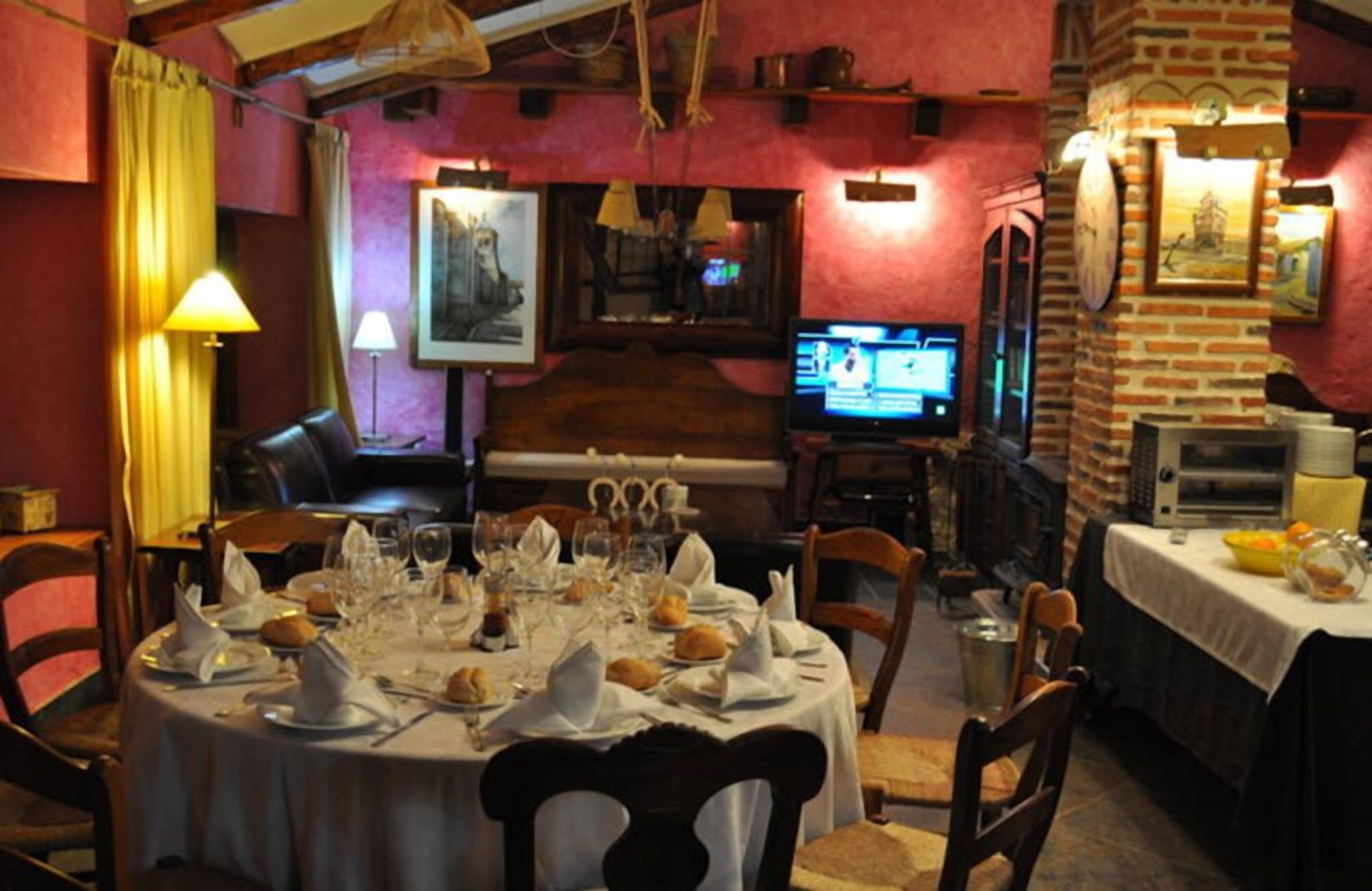 Een restaurant met een bakstenen muur, een televisietoestel en een gedekte tafel.