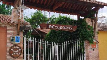 Una entrada tancada amb un cartell que diu "Bienvenidos" i un cartell per a "Asador las Cavas".