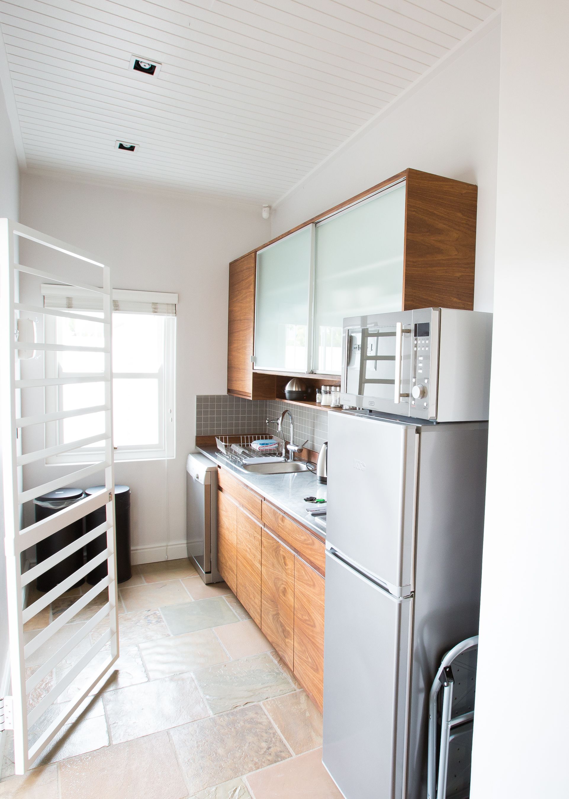 A modern kitchen with a built-in microwave, stainless steel appliances, and a window with blinds.