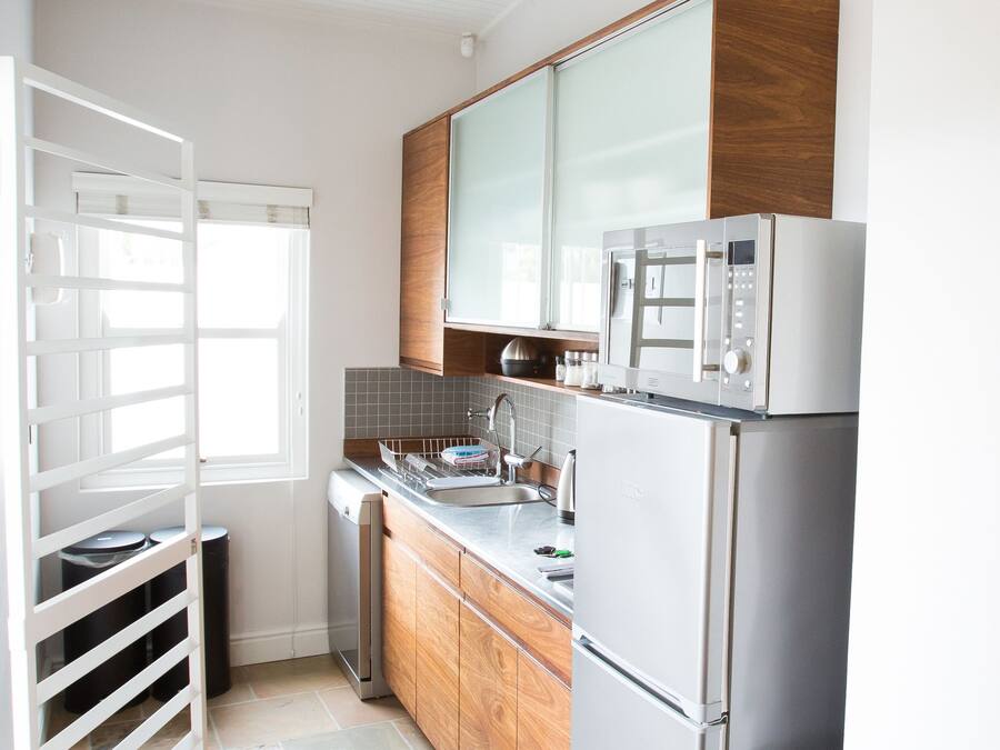 A modern kitchen with a built-in microwave, stainless steel appliances, and a window with blinds.