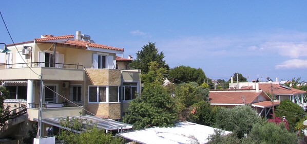 A residential building with a balcony, a solar water heater, and a red-tiled roof.