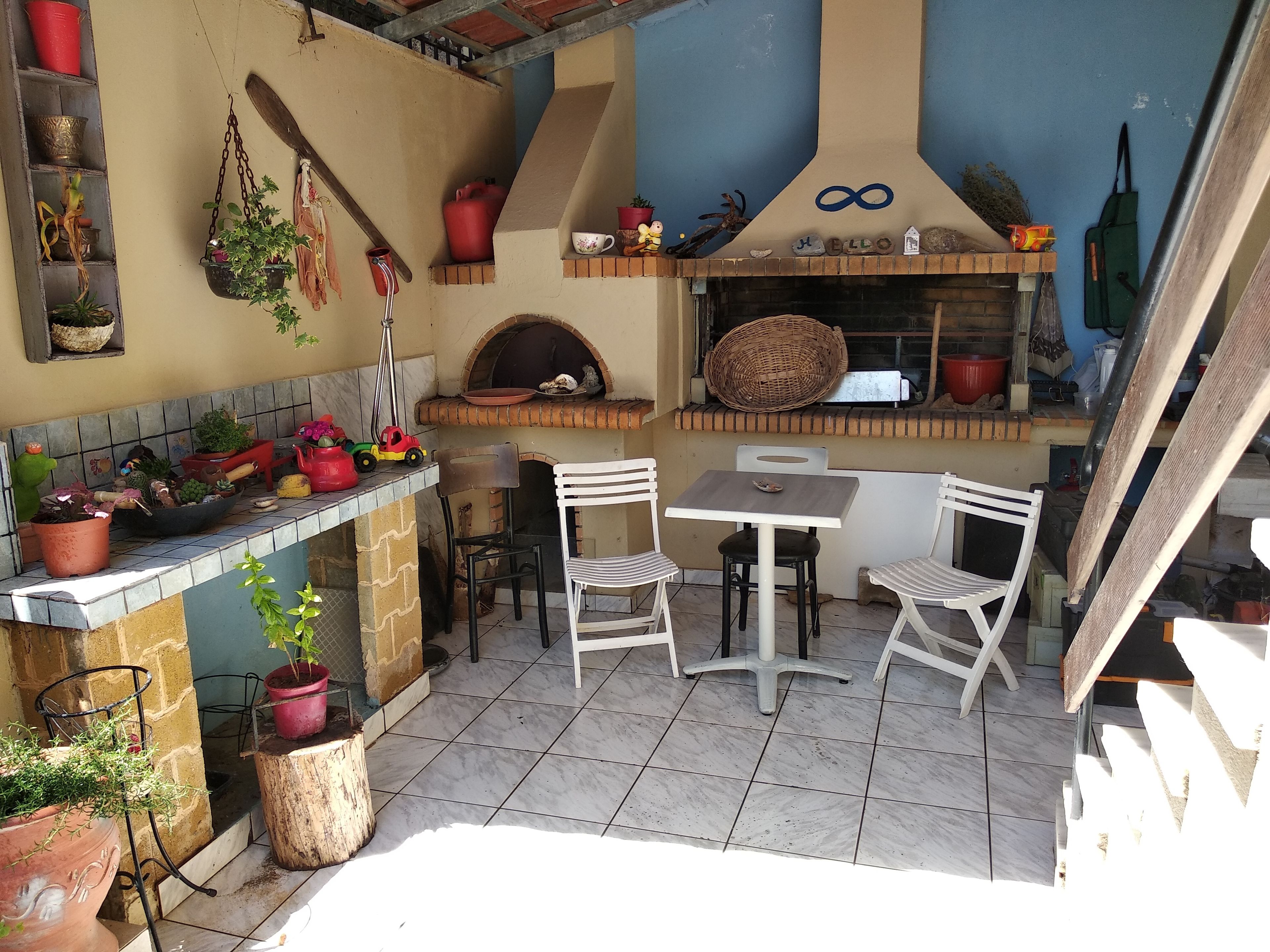 Un pequeño espacio de cocina al aire libre con un horno para pizza, una mesa y sillas.