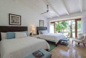 Une chambre d’hôtel avec deux lits, un ventilateur de plafond, une chaise et une vue sur l’extérieur.