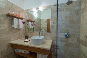 Une salle de bain avec un lavabo rond, un miroir, une douche et un porte-serviettes.