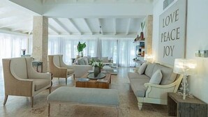 A spacious living room with a high ceiling, comfortable seating, and a motivational wall art saying "LOVE PEACE JOY". - Villa Emily (La Romana)