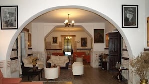 A spacious living room with a high arched ceiling, a fireplace, and a large window. There are multiple seating areas with sofas and armchairs. - Hostal La Mesnadita (Olmedo)