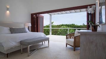 A bedroom with a bed, bench, and a view of the outdoors.