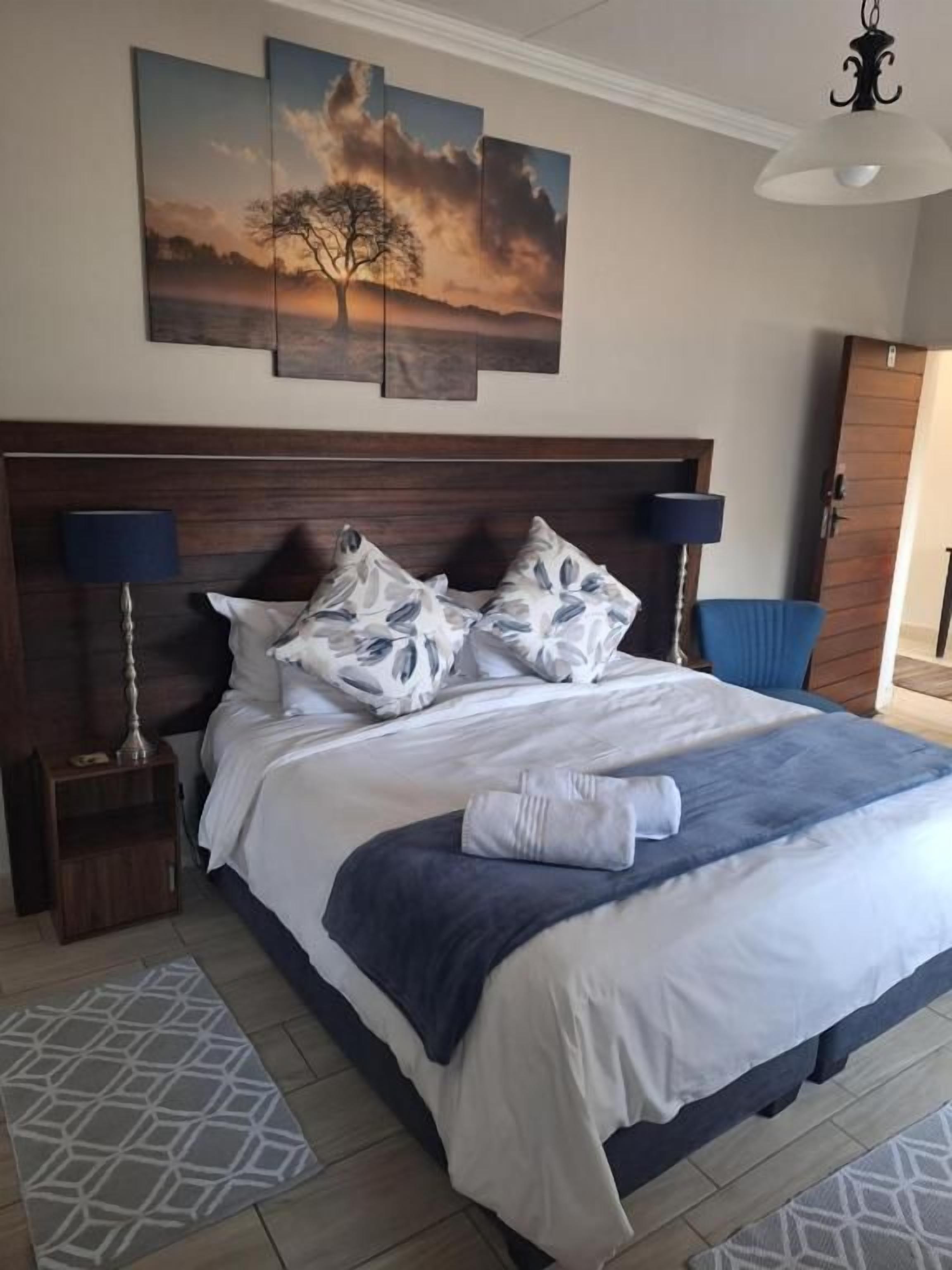 Una cama bien hecha con una decoración azul y blanca, un cabecero de madera y un cuadro en la pared superior.