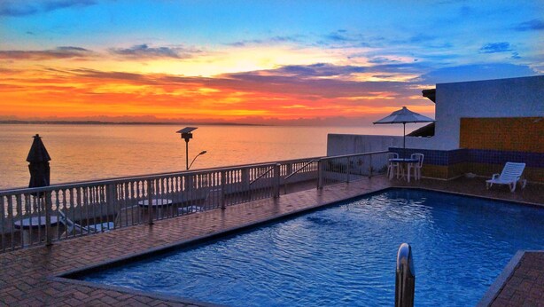 Une piscine avec vue sur la mer au coucher du soleil.