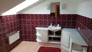 A bathroom with a white sink, a mirror, and a red-tiled wall. - Sinilille 7 Holiday Home (Kuressaare)