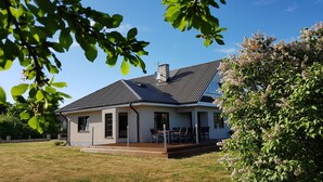 Ein zweistöckiges Haus mit Ziegelaußenwand, geneigtem Dach und einer Veranda mit Gartenmöbeln.