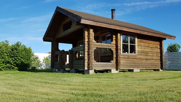 Eine Blockhütte mit Schornstein, großen Fenstern und einer Veranda.