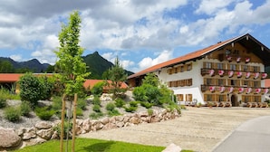 A traditional chalet with a stone facade, wooden balconies, and a mountain backdrop. - Zeller Hof (Ruhpolding)