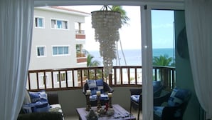 A balcony with a view of the ocean, furnished with a sofa, chairs, and a table. - Juan Dolio Apartment (Guayacanes)