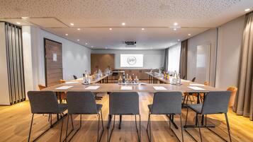 A conference room with a long table, grey chairs, and a projector screen displaying "Helds".