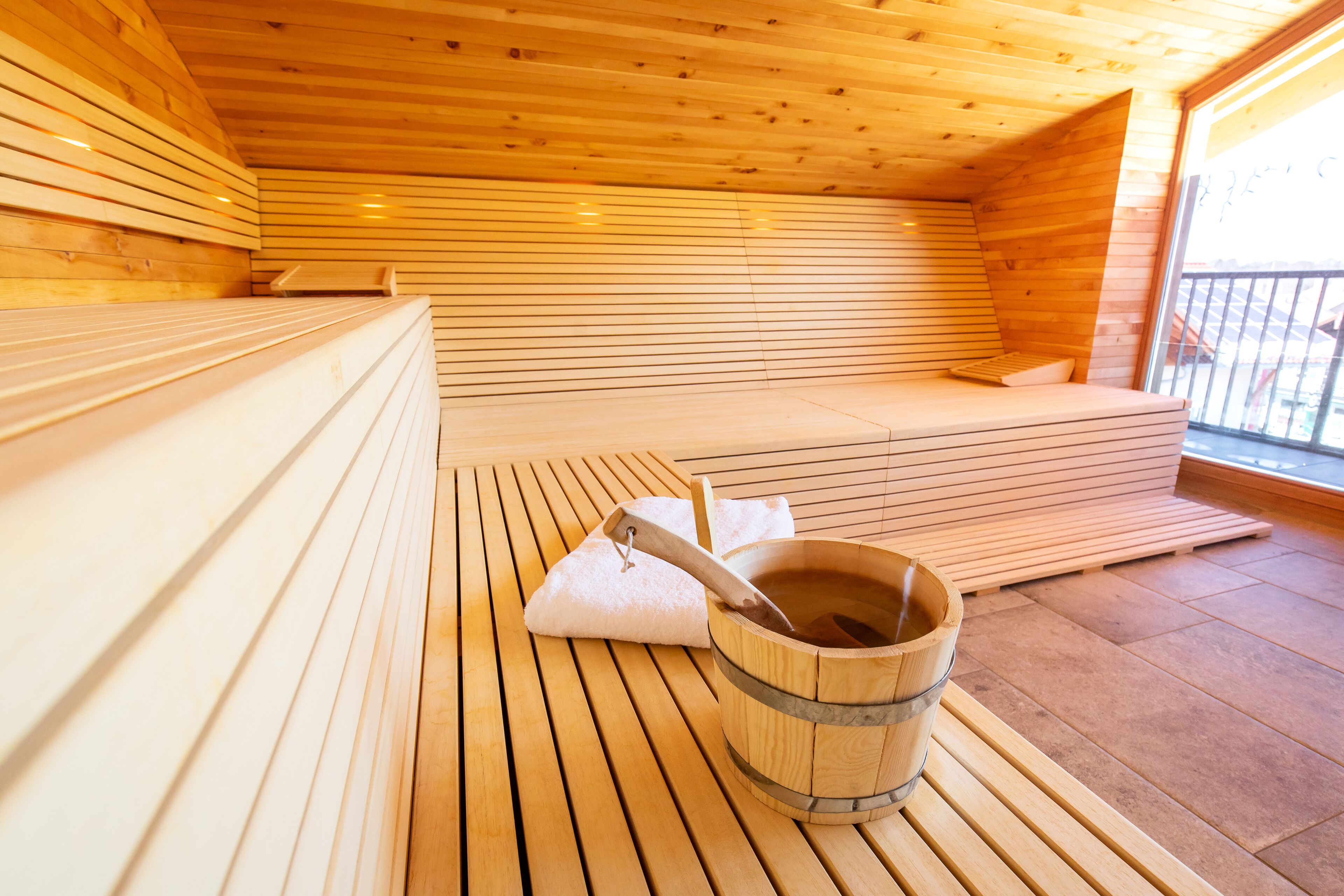 A wooden sauna room with benches and a wooden bucket.