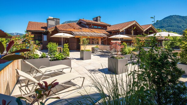 Una cabaña moderna con un patio, mobiliario exterior y vistas a la montaña.