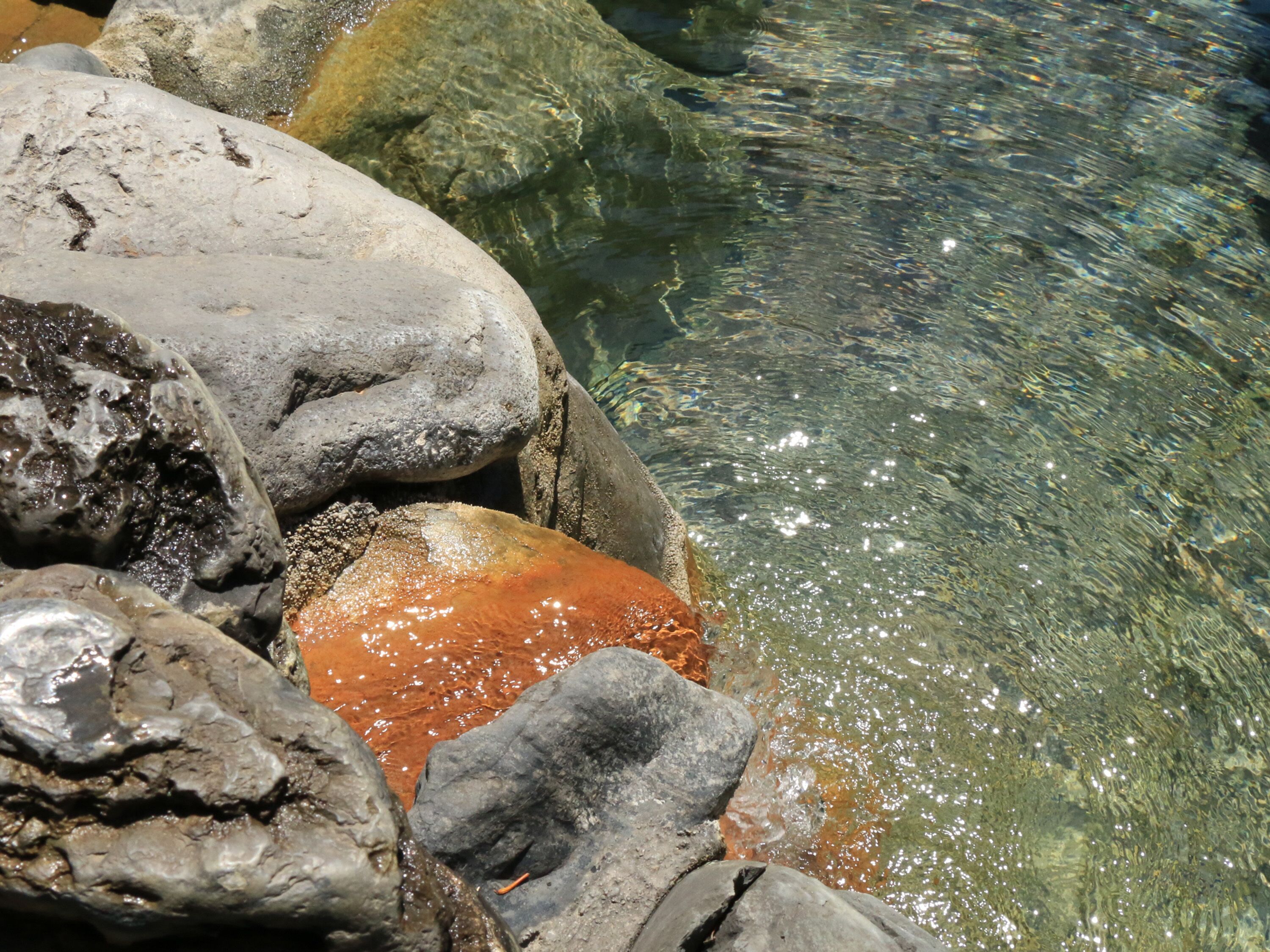 Ein felsiger Bach mit klarem Wasser und großen Steinen.