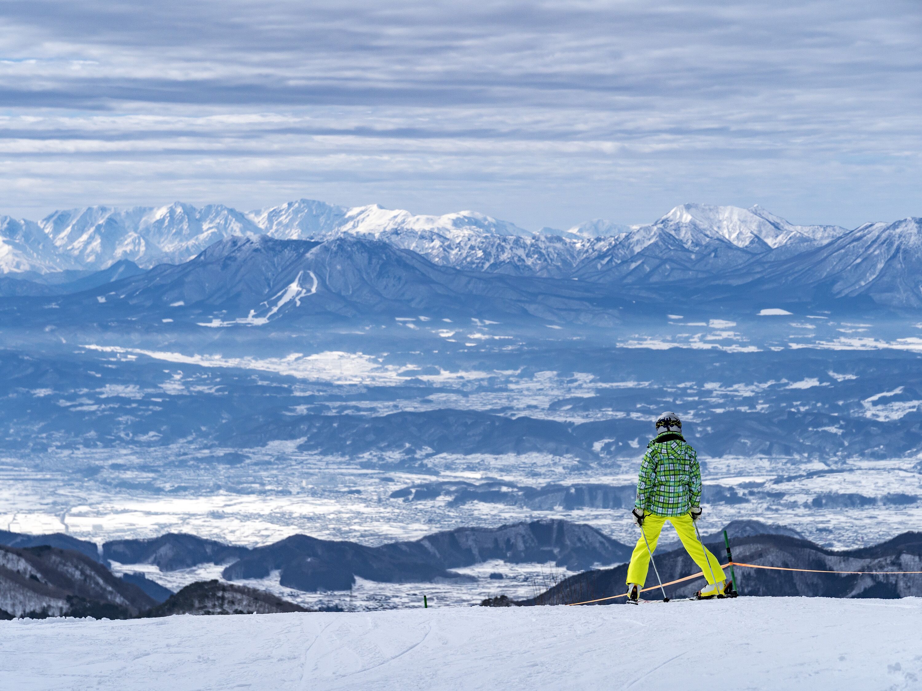 A person skiing on a snowy mountain with a view of snow-covered peaks in the background.