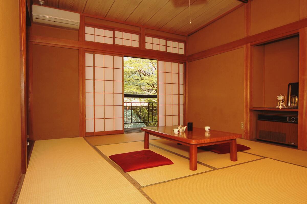 Una habitación tradicional japonesa con suelo de tatami, una mesa de madera baja y puertas correderas shoji.