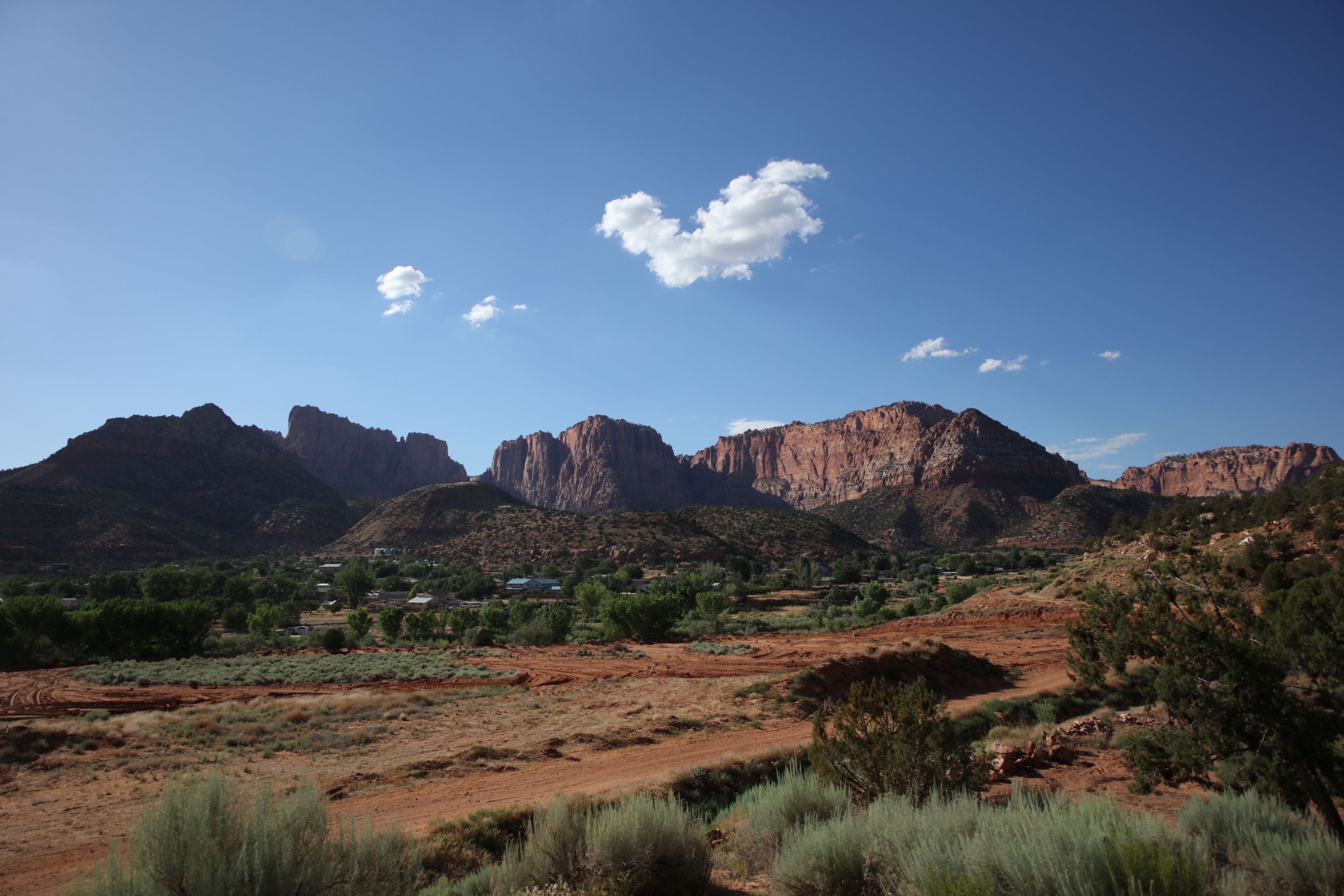 A desert landscape with mountains in the background and sparse vegetation in the foreground.
