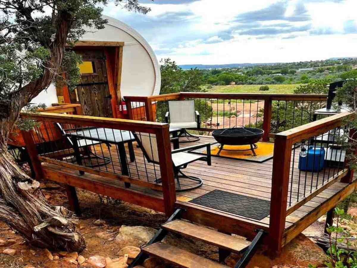A deck with outdoor furniture, a barbecue grill, and a view of a rural landscape.