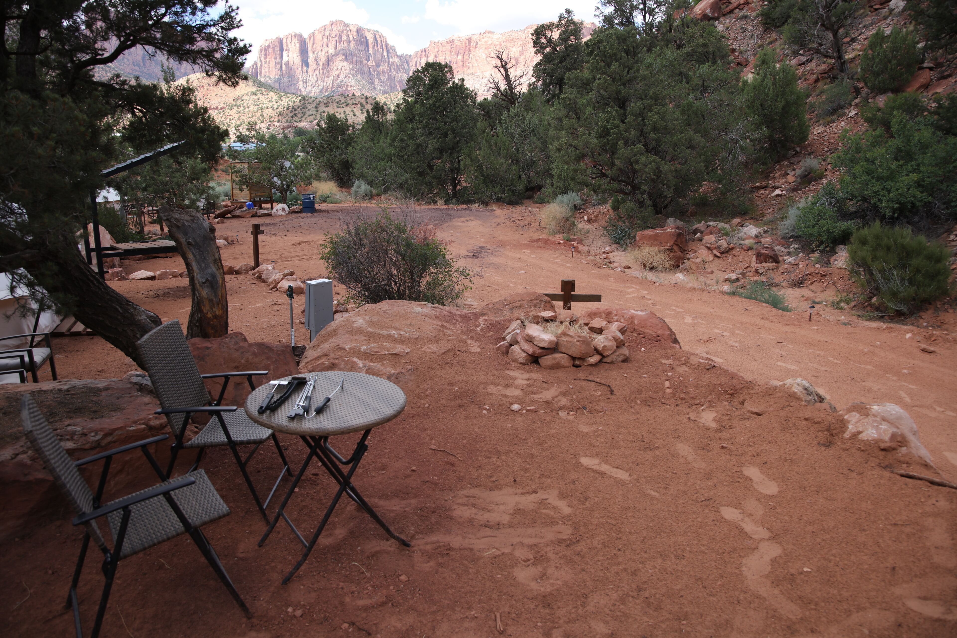 An outdoor seating area with a table and chairs, a fire pit, and a view of the surrounding landscape.