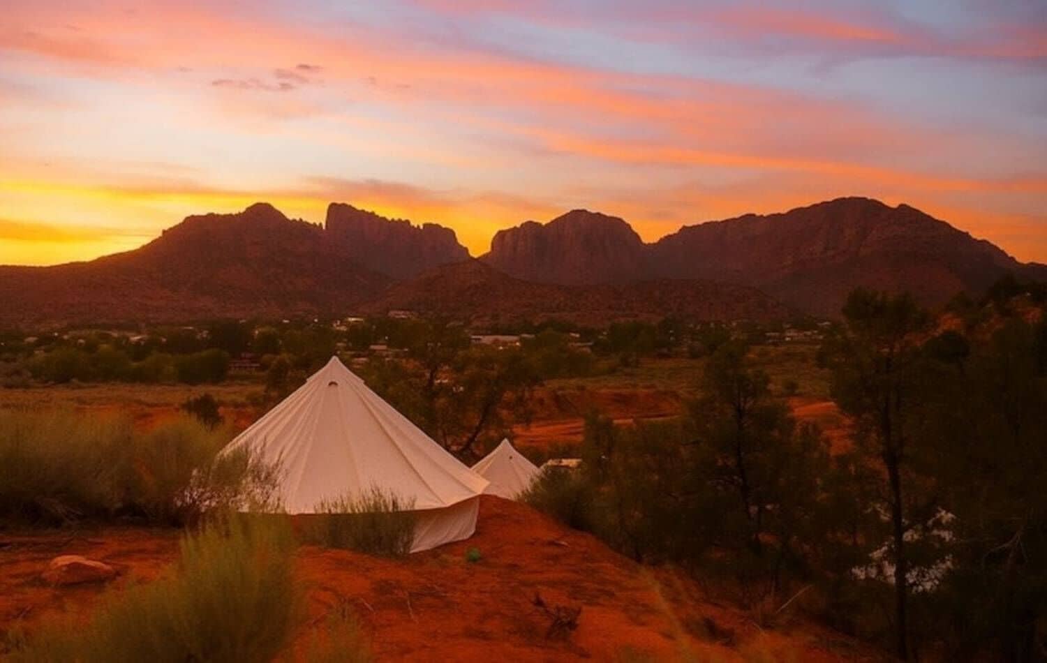 A desert landscape with two white tents and a mountain range in the background.