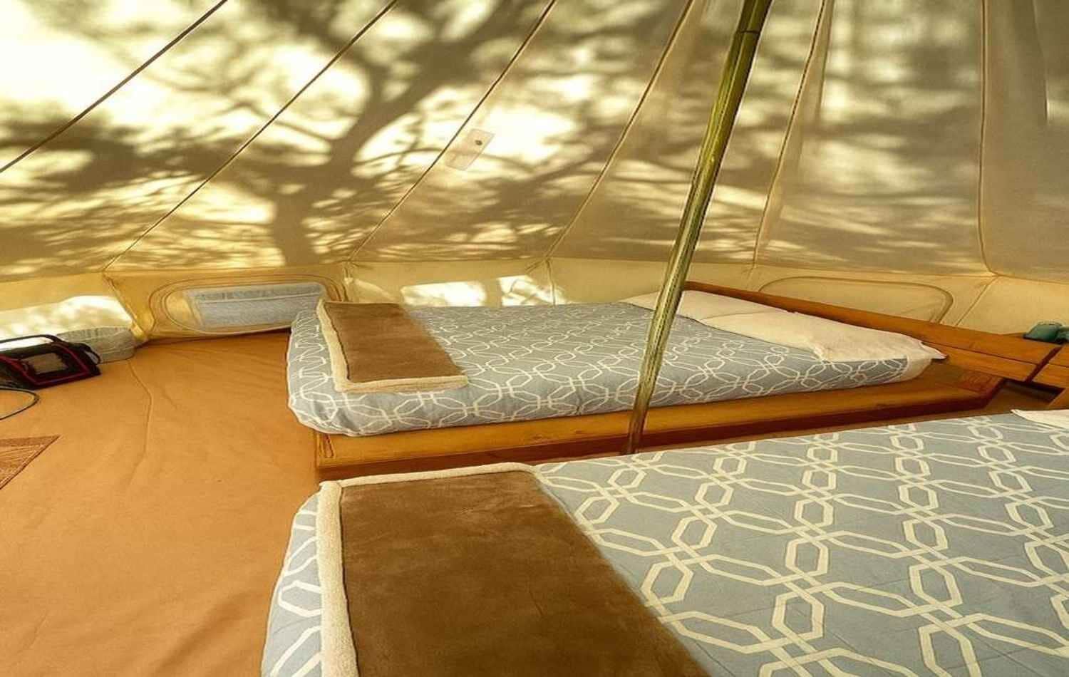 Une tente dotée de deux espaces de couchage, chacun comprenant un matelas à motifs et un oreiller.
