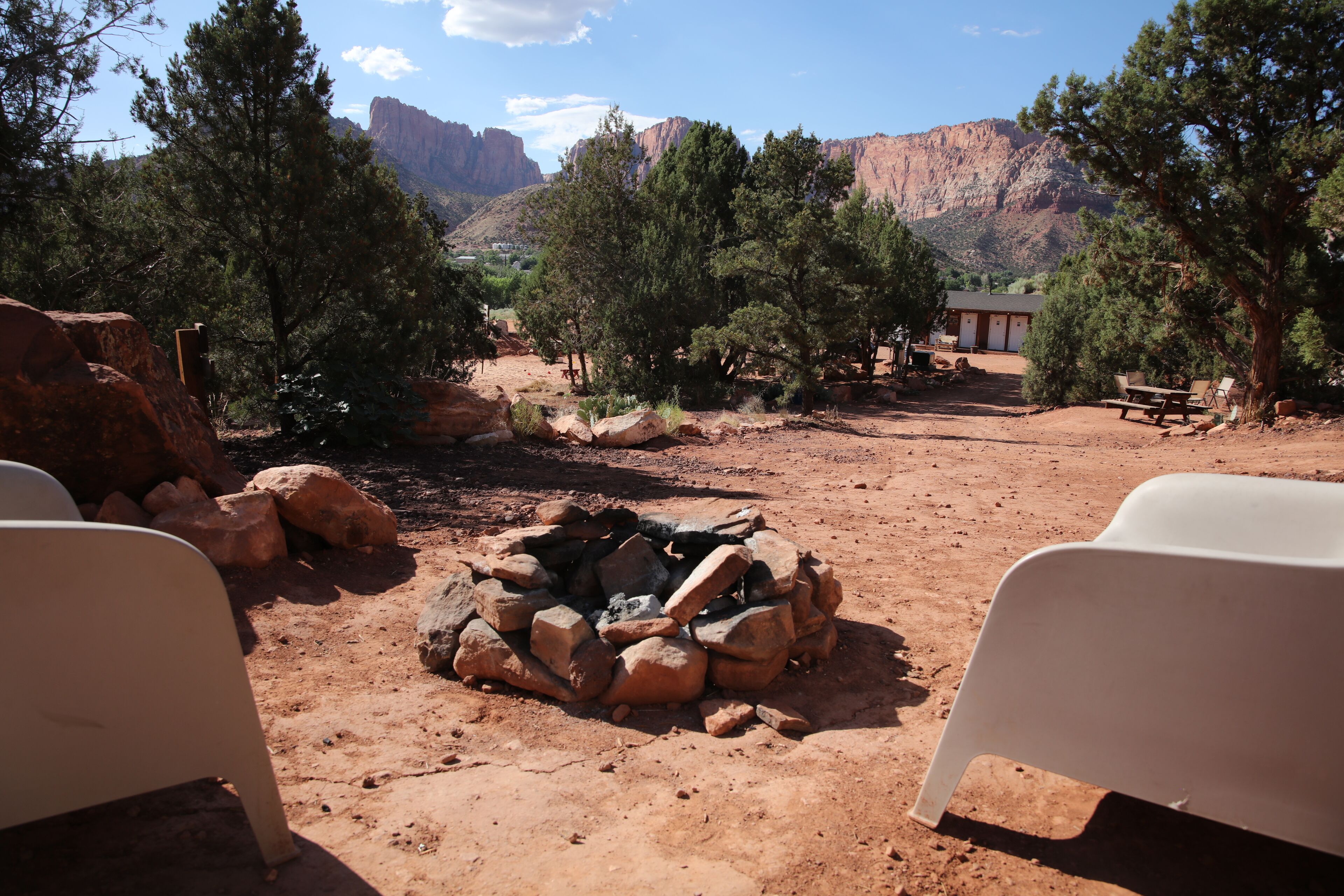 A campsite with a fire pit, trees, and a mountain in the background.