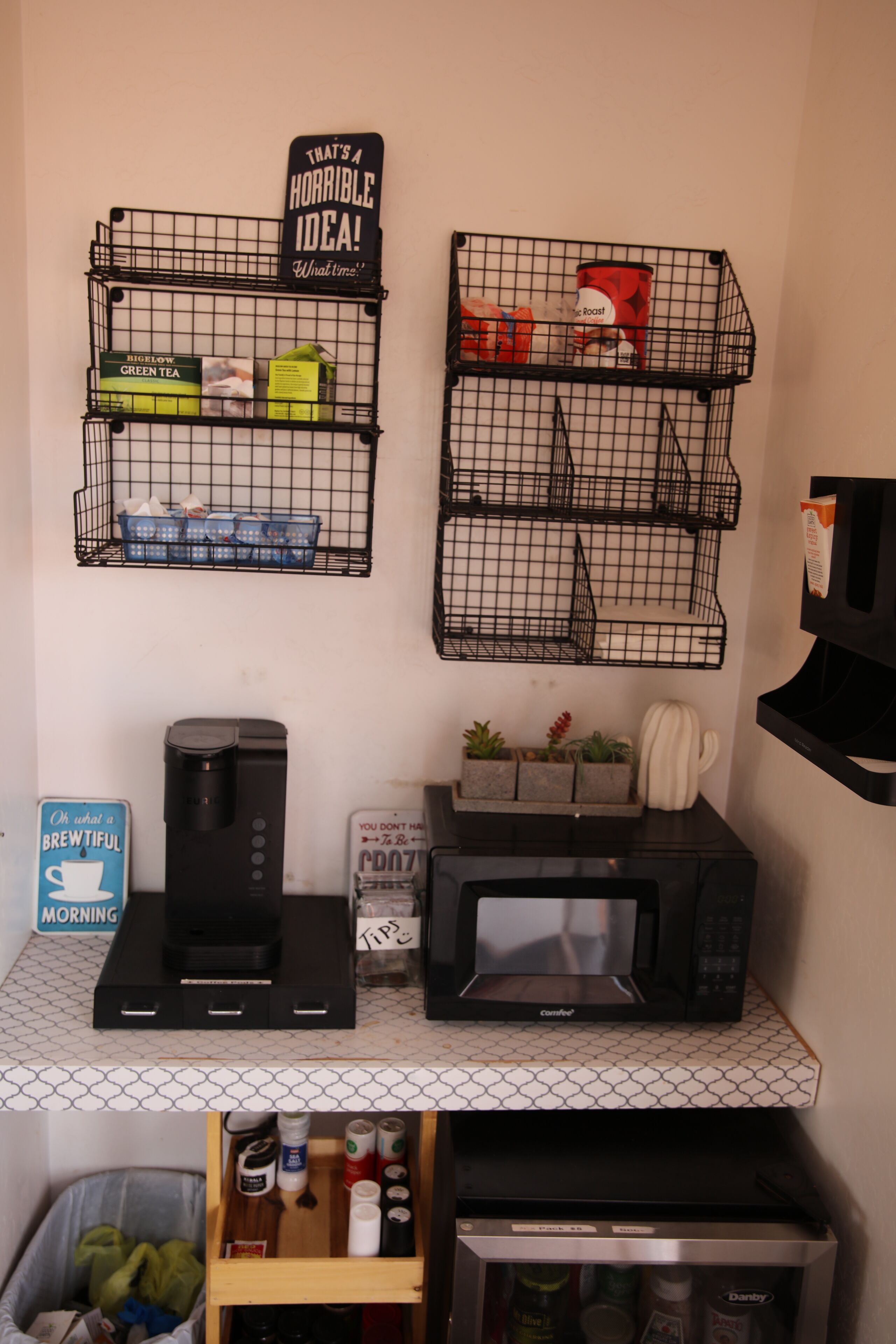 A kitchen with a coffee maker, microwave, and shelves with kitchen items.