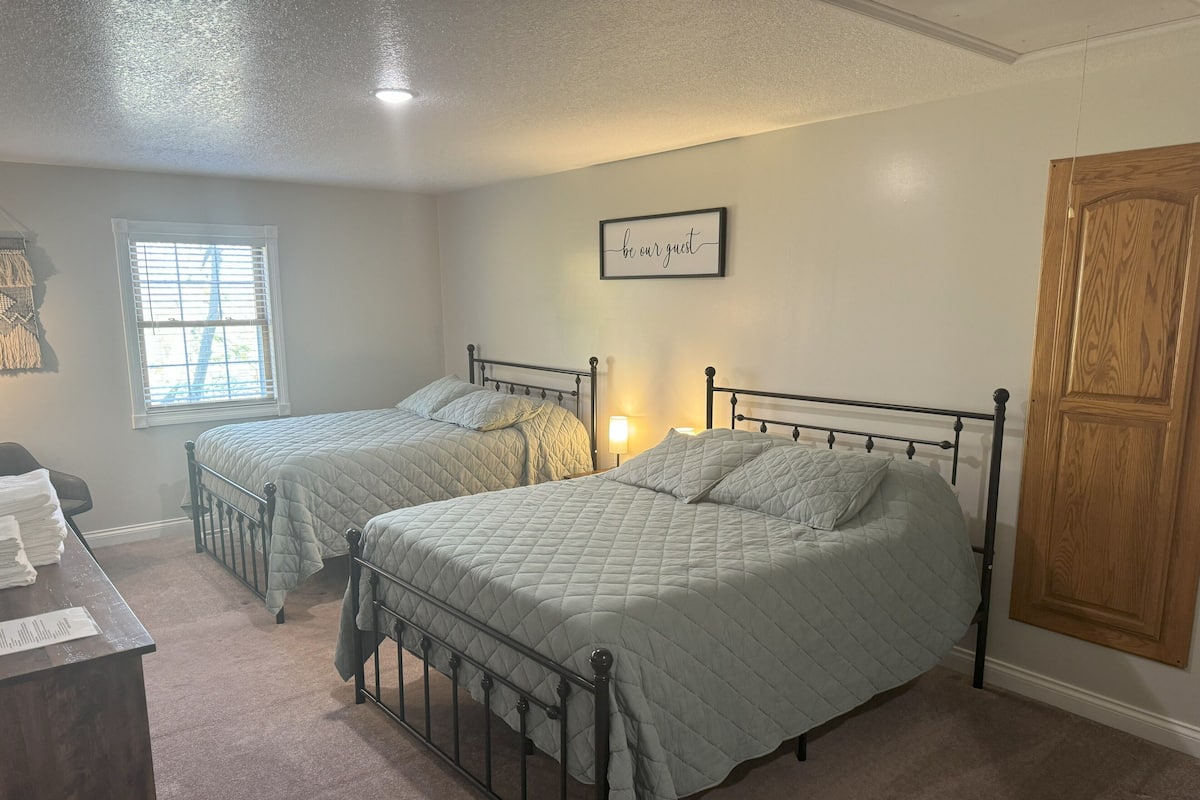 A bedroom with two beds, a wooden door, a window, and a wall sign.