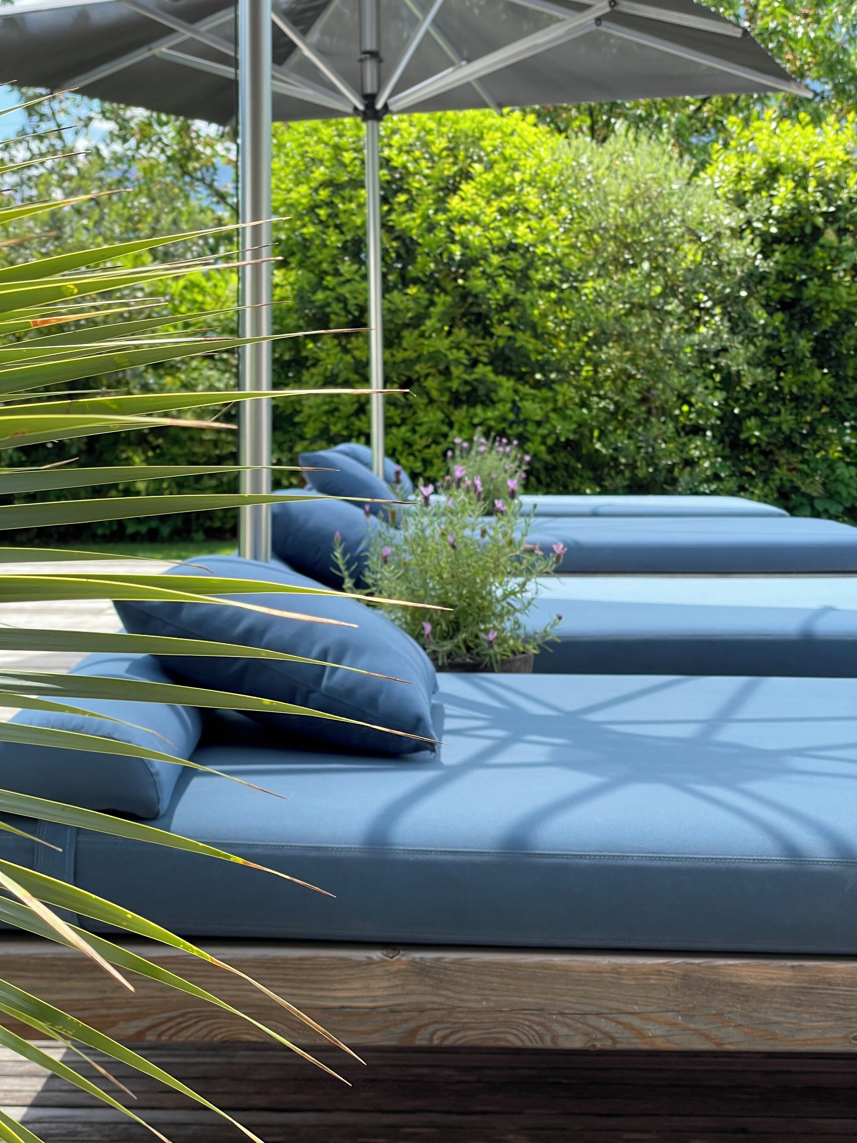 A modern outdoor seating area with blue cushions and a metal umbrella.